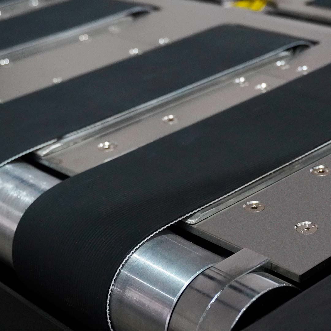 Detalhe da esteira motorizada com faixas pretas e placas metálicas da SPI-8560B